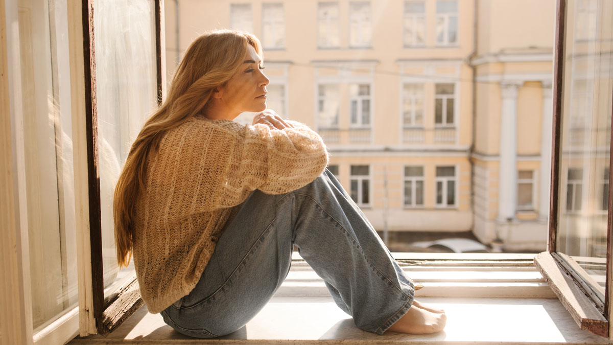 woman sitting by window stuck in rumination